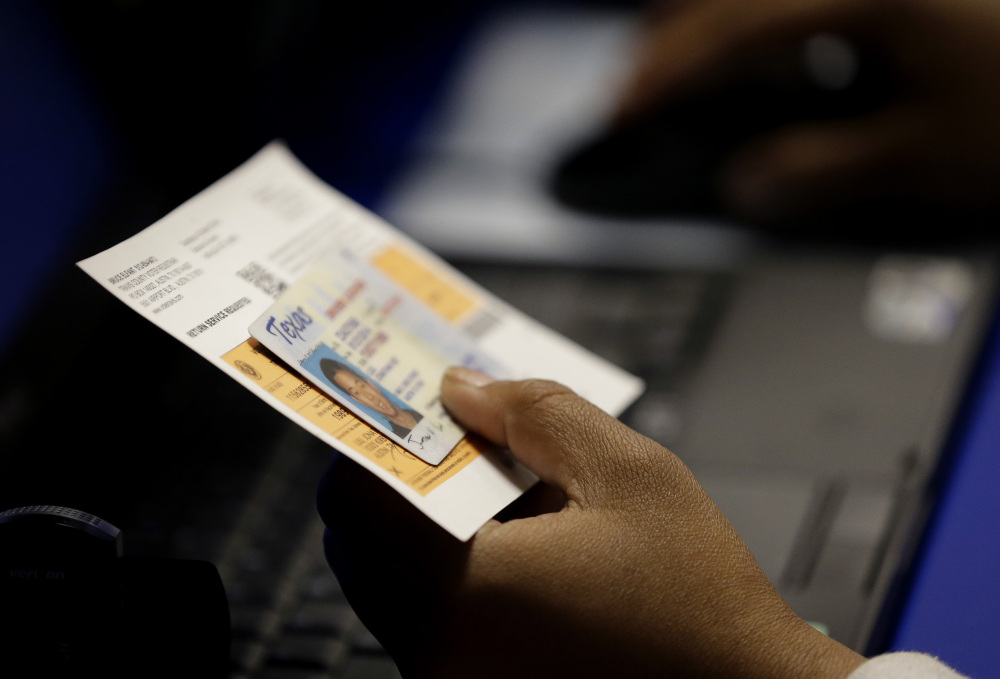 In this Feb. 26, 2014 file photo, an election official checks a voter’s photo identification at an early voting polling site in Austin, Texas.