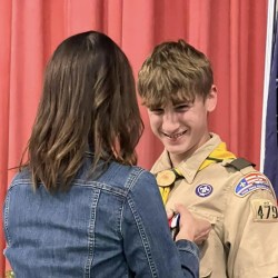 Nathan and Lee: Nathan receives the Eagle Scout Charge from Lee Pettengill who is the Chartered Organization Representative for Troop 479 and served as Master of Ceremonies for the Eagle Court of Honor Ceremony. Nathan: Nathan Choate, Eagle Scout, makes the Scout Sign during his Eagle Scout Ceremony Stephanie pins Nathan: Stephanie Drake Choate pins the Eagle Scout medal onto her son's uniform. "It was so special to have it at Mount Merici Academy. We are so proud of you, Nathan," she said. Joe and Nathan: Joe Doore of the Town of Albion spoke about why Nathan received the Spirit of America Award from the Town of Albion earlier this year. Elijay Parish Lovejoy was born in Albion in 1802 and was an American newspaper editor who was killed by a mob for his firm, published positions denouncing slavery in 1837. Nathan's Eagle Scout Project restored the marker in Albion commemorating Lovejoy.